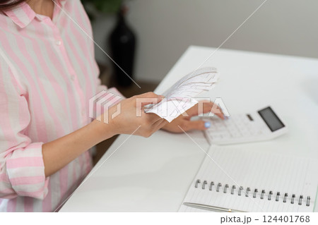 Analyzing Expenditures and Home Office Routine. A woman calculating expenses with her receipts and calculator at her desk. 124401768