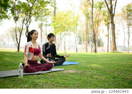 Man and woman practicing meditation together in a park. Mindfulness and mental health concept Man and woman practicing meditation together in a park. Mindfulness and mental health concept 124401943