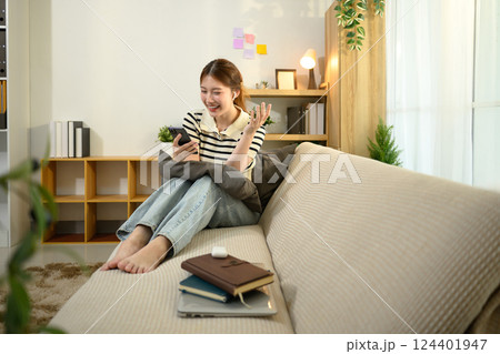 Young woman smiling during a video call while sitting on sofa at home Young woman smiling during a video call while sitting on sofa at home 124401947