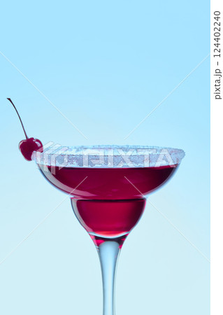 Cherry cocktail in elegant glass with sweet and sour rim against bright blue background. Concept of vacation, cocktails Cherry cocktail in elegant glass with sweet and sour rim against bright blue background. Concept of vacation, cocktails 124402240
