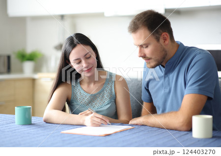 Interracial roommates signing paper contract at home Interracial roommates signing paper contract at home 124403270