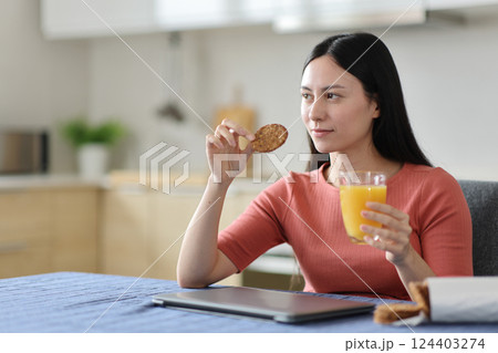 Serious asian woman at breakfast in the kitchen Serious asian woman at breakfast in the kitchen 124403274