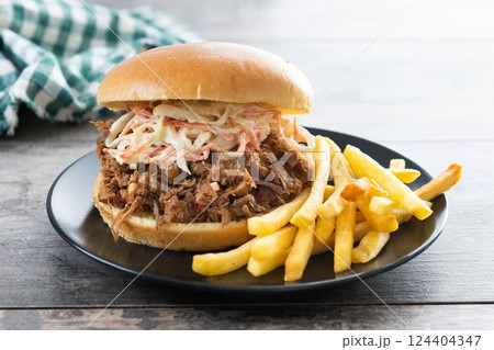 Pulled pork sandwich with coleslaw salad and french fries on wooen table Pulled pork sandwich with coleslaw salad and french fries on wooen table 124404347