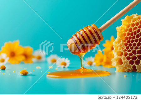 A honey dipper with honey dripping from it next to a honeycomb 124405172