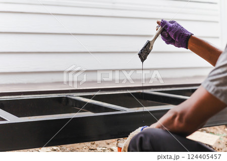 Hand holding paint bush painting anti rust paint on steel at home decorated. Hand holding paint bush painting anti rust paint on steel at home decorated. 124405457