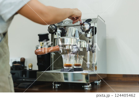 Hands of female barista pressing button on machine while making fresh coffee.. 124405462