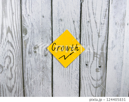Bright sticky note displaying the word Growth, placed on textured wooden background, symbolizing personal development and progress in life 124405831