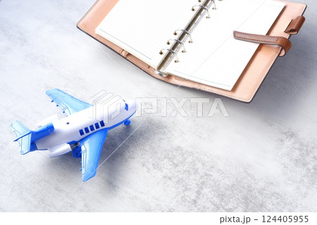 飛行機と、開いたリング式のシステム手帳で、次の長期休暇に旅行を計画しているイメージ 124405955