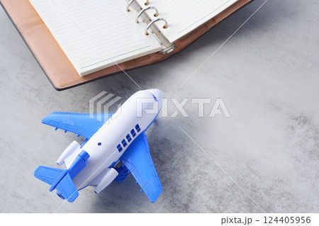飛行機と、開いたリング式のシステム手帳で、次の長期休暇に旅行を計画しているイメージ 飛行機と、開いたリング式のシステム手帳で、次の長期休暇に旅行を計画しているイメージ 124405956