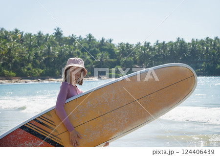 Happy woman surfer with surfboard looking at camera. Her face is protected by natural spf surf zinc. Outdoors. Summer tropical vacation. 124406439
