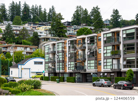 A perfect neighborhood. Uphill residential area with cars parked on the streets around the building 124406559