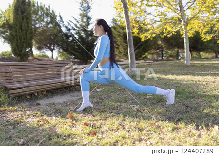 Young sportswoman stretching legs in a park before running 124407289