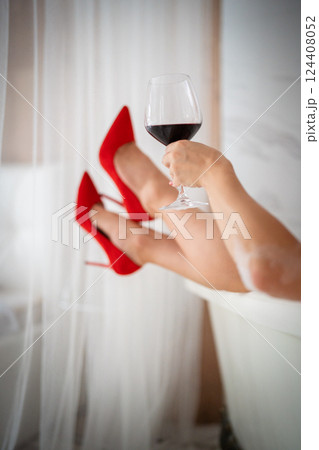 Beautiful woman legs in red high heel shoes with red wine. 124408052
