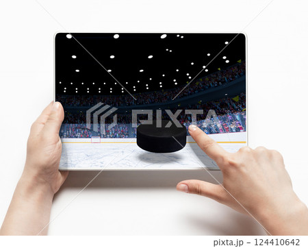 Person with tablet showing hockey game. Tapping screen with virtual puck and ring. Digital sport entertainment, sports apps, gaming platforms 124410642