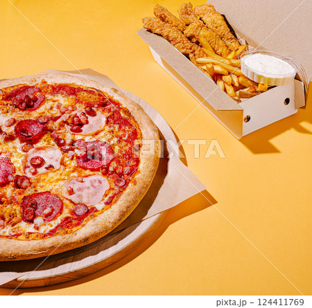 Delicious pepperoni pizza with crispy fried chicken and fries 124411769