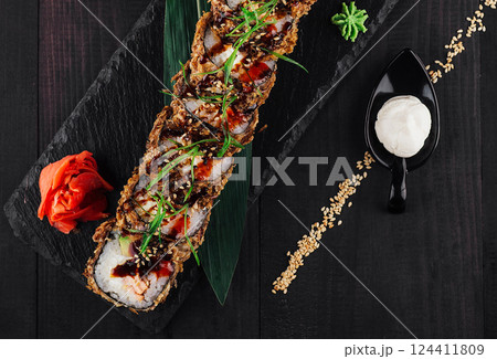Tempura sushi roll being served on a black slate platter 124411809