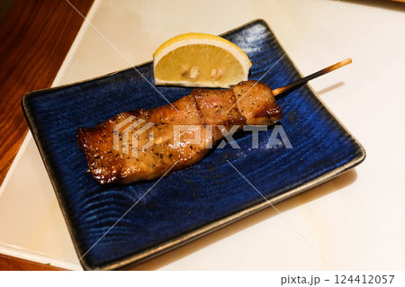 close up of grilled Japanese wagyu beef ox tongue skewer yakitori on a blue plate with lemon slice on the side in a izakaya restaurant  124412057