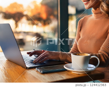 カフェでノートパソコン操作する女性の手元 124412363