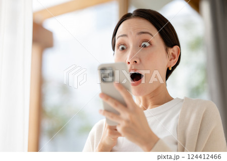 スマホを見て驚く女性 スマホを見て驚く女性 124412466