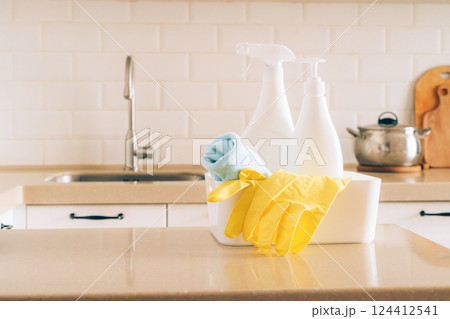 Cleaning supplies on kitchen counter with yellow gloves and spray bottles 124412541
