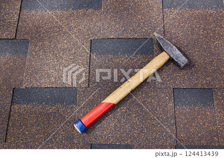 Hammer on the soft roof tiles on the roof of the building. Copy space. Hammer on the soft roof tiles on the roof of the building. Copy space. 124413439