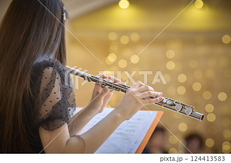 Flute Player Practicing with Sheet Music in Concert Hall. Copy space 124413583