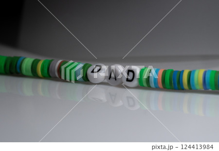 Green Bracelet Displaying Word "Dad" on Glossy Surface with Reflection 124413984