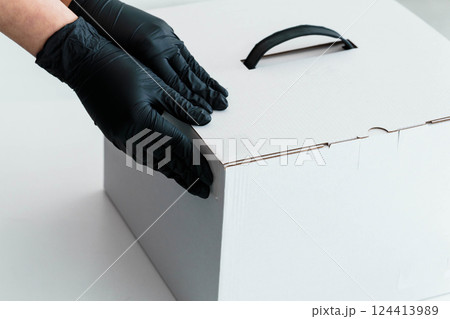 Gloved Hands Securing White Cardboard Box for Safe Delivery and Handling 124413989