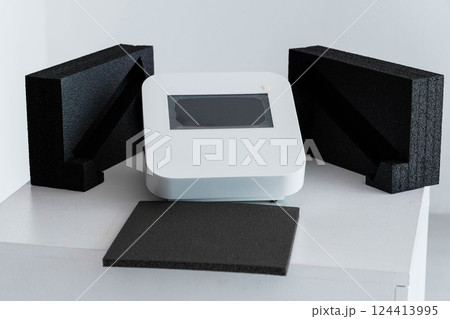 Modern Tech Device with Protective Black Foam Packaging on White Table 124413995