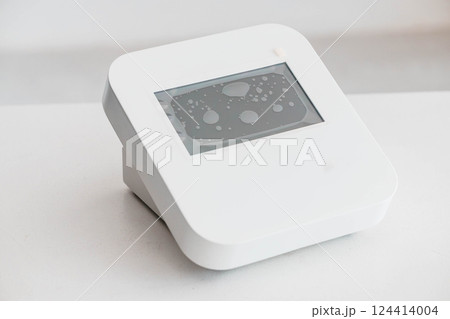 Modern White Digital Device with Display Showing Water Droplets on Screen Modern White Digital Device with Display Showing Water Droplets on Screen 124414004