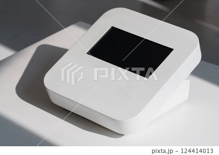 Modern Minimalistic White Digital Touchscreen Device on Table with Sunlight Shadows 124414013