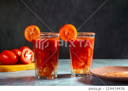 Two Bloody Mary cocktails in glass served with tomato slice and salt on dark background. Red cocktail. Alternative taste. Dirty dump drink 124414436
