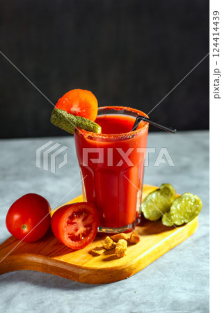 Vegetable shaken cocktail in glass on dark grey background. Red tomato cocktail. Served with tomatoes and pickles. Vegan menu. 124414439