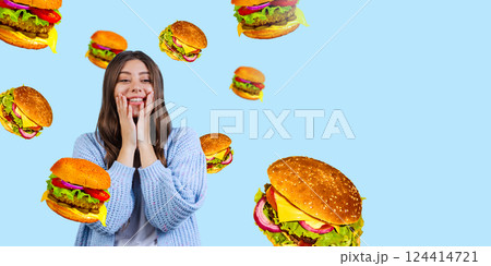 Girl in cozy sweater looking amazed while surrounded by floating burgers on bright blue background. 124414721
