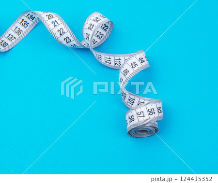 White measure tape on blue backgrond with copyspace 124415352