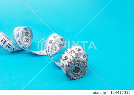 White measure tape on blue backgrond with copyspace White measure tape on blue backgrond with copyspace 124415353