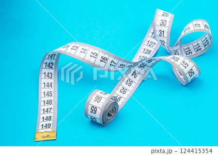 White measure tape on blue backgrond with copyspace White measure tape on blue backgrond with copyspace 124415354
