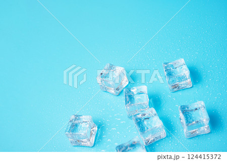 Ice cubes with water drops scattered on a blue background, top view. Ice cubes with water drops scattered on a blue background, top view. 124415372
