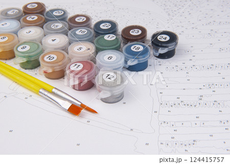 A set of colorful gouache paints, brushes and canvas with numbers is ready for drawing education. Hobby and leisure activity. Background with copy space 124415757