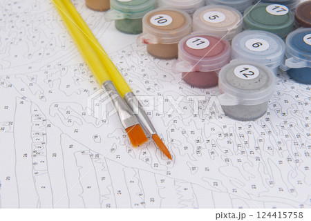 A set of colorful gouache paints, brushes and canvas with numbers is ready for drawing education. Hobby and leisure activity. Background with copy space 124415758