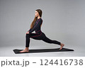Slim woman in black bodysuit exercising on gym mat. Side view of calm Caucasian girl with long hair, practicing yoga, isolated on grey studio background. Concept of yoga, sport, healthy lifestyle. 124416738