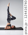 Mindful young woman performing Sarvangasana yoga pose in studio. Side view of attractive female in activewear practicing supported shoulder stand pose with bent leg, isolated on grey. Yoga concept. 124416740