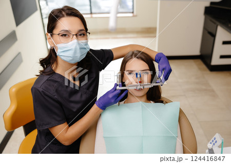 Female dentist trying on a facial arch for a patient sitting in a dental chair Female dentist trying on a facial arch for a patient sitting in a dental chair 124416847