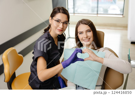 Doctor and patient are doing heart with hands in office. The doctor is grateful for the trust 124416850