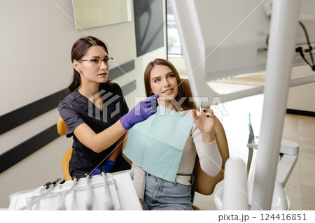 Dentist talking and showing results of x-ray teeth on screen to patient in dental chair. Treatment, healthcare and medicine Dentist talking and showing results of x-ray teeth on screen to patient in dental chair. Treatment, healthcare and medicine 124416851