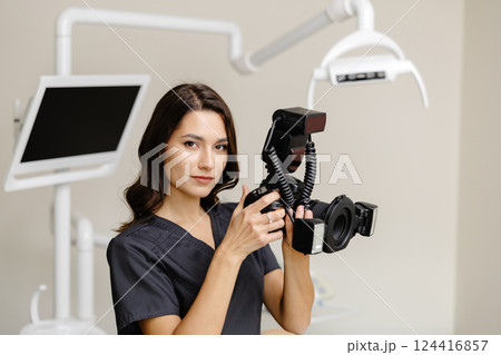 Woman dentist holding camera in hands and taking photos of patient teeth at modern clinic 124416857