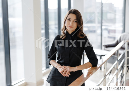 Young female doctor is standing in a hospital hall and looking at the camera Young female doctor is standing in a hospital hall and looking at the camera 124416861