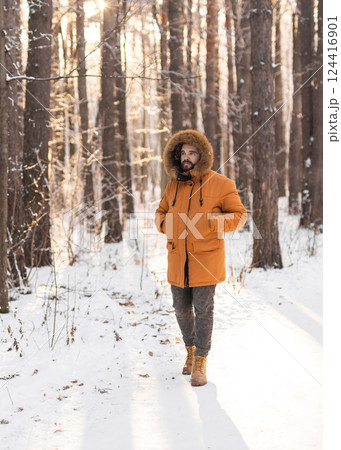 Man walking along snowy path in winter forest. Mindfulness, seasonal change, and harmony with nature during a peaceful outdoor moment. Man walking along snowy path in winter forest. Mindfulness, seasonal change, and harmony with nature during a peaceful outdoor moment. 124416901