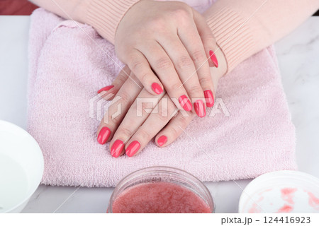 Close-up of woman's hands with manicure on pink towel. Close-up of woman's hands with manicure on pink towel. 124416923