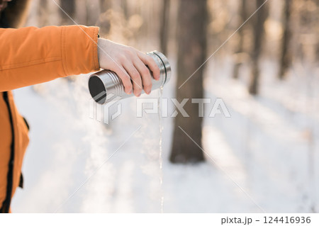 Hot drink poured from thermos into winter forest air. Contrast between warmth and cold, highlighting seasonal rituals and sensory moments. Copy space 124416936